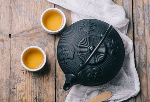 Traditional japanese herbal tea recipe prepared in cast iron teapot with organic dry herbs from above. Top view of asian traditional hot beverage on wooden table.