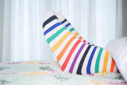Vibrant, striped socks are laid out on a bed, creating a cozy vibe.