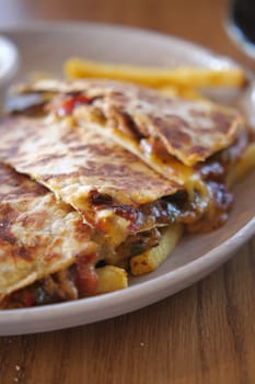 Melted cheese with vegetables in a warm quesadilla paired with fries