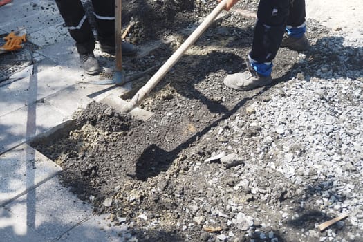 Laborers excavate soil and gravel at a construction site during the day.