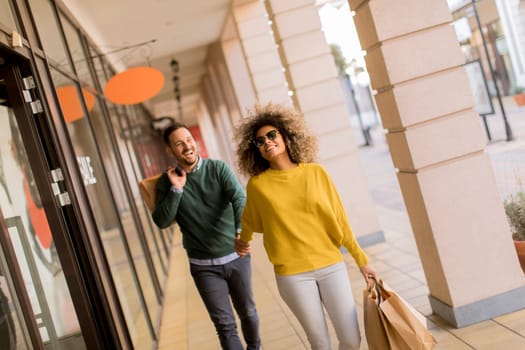 Beautiful young multiethnic couple with paper bags enjoying in shopping, having fun in the city