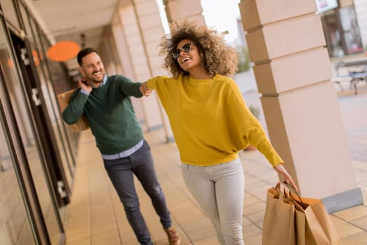 Beautiful young multiethnic couple with paper bags enjoying in shopping, having fun in the city