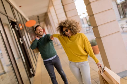 Beautiful young multiethnic couple with paper bags enjoying in shopping, having fun in the city