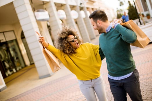 Lovely young multiethnic couple with bags in the shopping