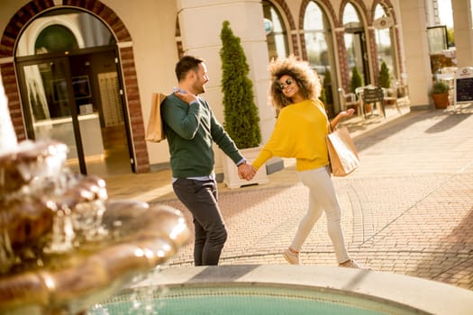 Young multiethnic couple walking by the fountain on a sunny day