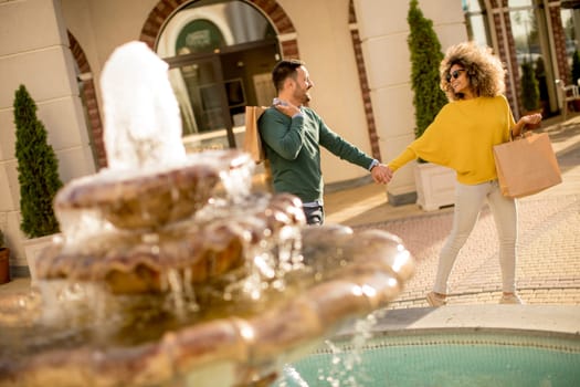 Young multiethnic couple walking by the fountain on a sunny day