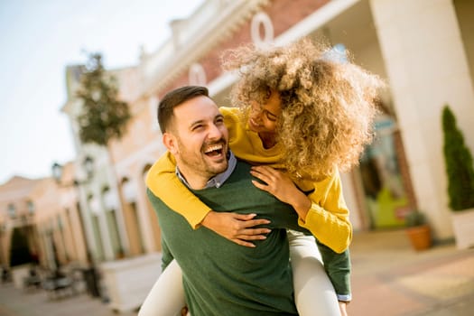 Young man holds a young woman on his back and entertaining themselvs outdoor