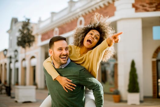 Young man holds a young woman on his back and entertaining themselvs outdoor