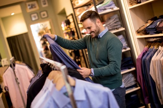 Handsome young man buying shirt in the store