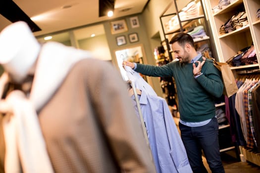 Handsome young man buying shirt in the store