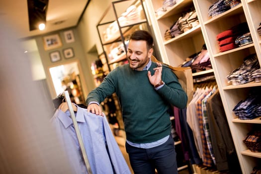 Handsome young man buying shirt in the store