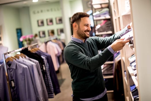 Handsome young man buying clothes in the store