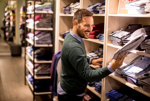 Handsome young man buying clothes in the store