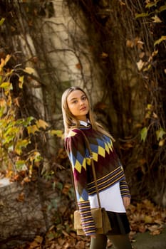 Pretty young woman standing in autumn park