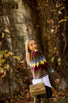 Pretty young woman standing in autumn park
