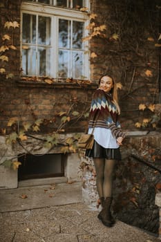 Pretty young woman standing outside at sunny autumn day