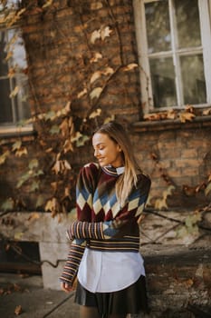 Pretty young woman standing outside at sunny autumn day
