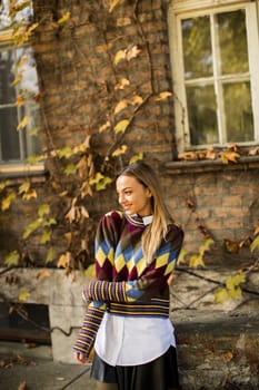 Pretty young woman standing outside at sunny autumn day