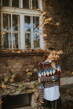 Pretty young woman standing outside at sunny autumn day