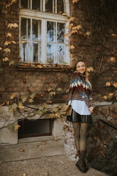 Pretty young woman standing outside at sunny autumn day