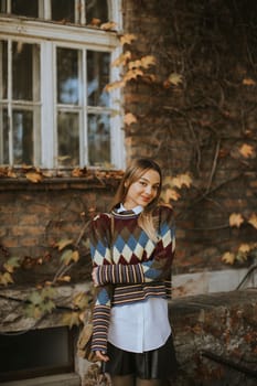 Pretty young woman standing outside at sunny autumn day