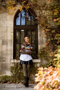 Pretty young woman standing outside at sunny autumn day
