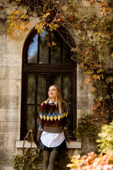 Pretty young woman standing outside at sunny autumn day