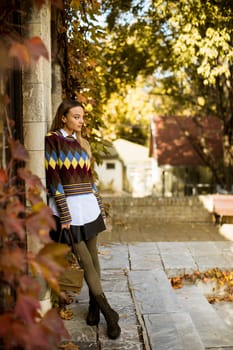 Pretty young woman standing outside at sunny autumn day
