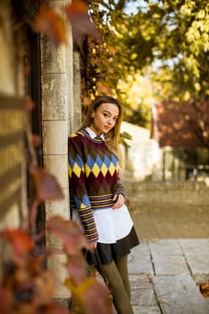 Pretty young woman standing outside at sunny autumn day