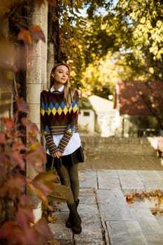 Pretty young woman standing outside at sunny autumn day