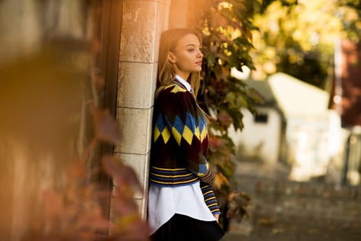 Pretty young woman standing outside at sunny autumn day