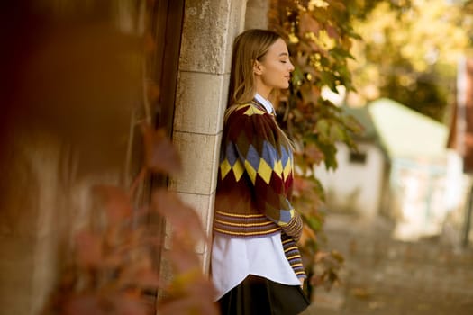 Pretty young woman standing outside at sunny autumn day