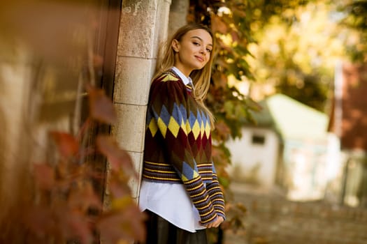 Pretty young woman standing outside at sunny autumn day