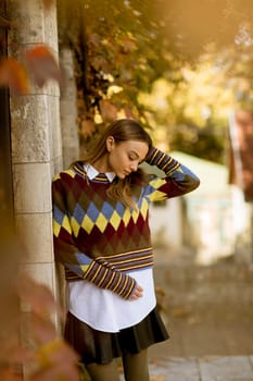 Pretty young woman standing outside at sunny autumn day