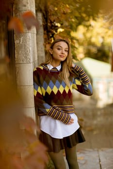 Pretty young woman standing outside at sunny autumn day