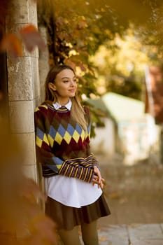 Pretty young woman standing outside at sunny autumn day