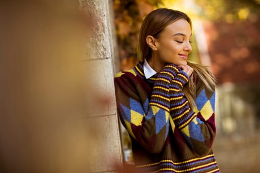 Pretty young woman standing outside at sunny autumn day