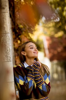 Pretty young woman standing outside at sunny autumn day