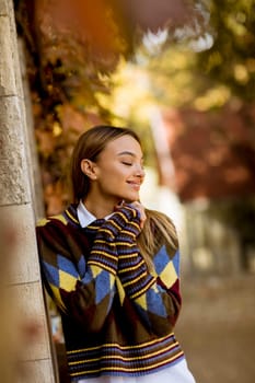Pretty young woman standing outside at sunny autumn day
