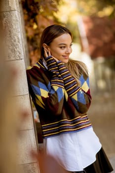 Pretty young woman standing outside at sunny autumn day