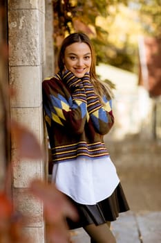 Pretty young woman standing outside at sunny autumn day