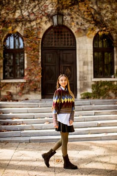 Pretty young woman walking in the autumn park on a sunny day