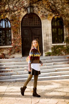 Pretty young woman walking in the autumn park on a sunny day