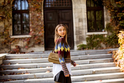 Pretty young woman walking in the autumn park on a sunny day