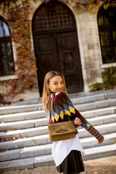 Pretty young woman standing outside at sunny autumn day
