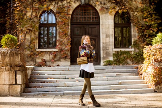 Pretty young woman walking in the autumn park on a sunny day
