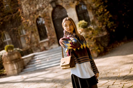 Pretty young woman standing outside at sunny autumn day