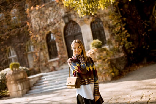 Pretty young woman standing outside at sunny autumn day