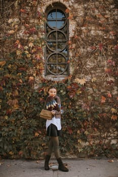 Pretty young woman standing outside at sunny autumn day