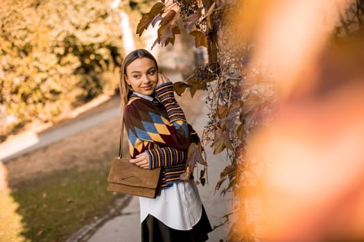 Pretty young woman standing outside at sunny autumn day